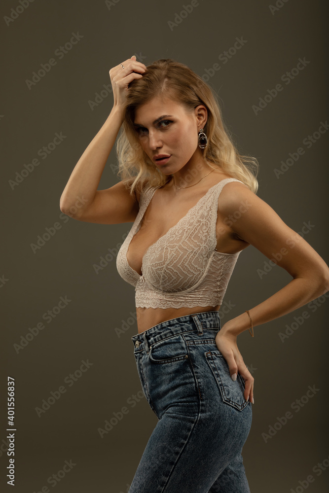 Close up of beautiful young woman with long blonde hair. Wears just beige bra and fashion stylish jeans. Close up of beautiful young woman with long blonde hair. Wears just beige bra and fashion stylish jeans.