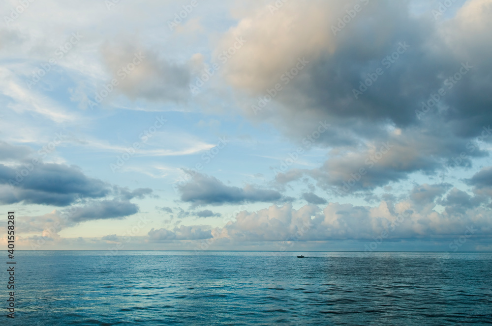 Nightfall over Caribbean sea. Deep ocean view with waves and white clouds. Relaxing seascape, endless sea, tropical waters background. Blue seas and cloudy skies separated by a far away horizon
