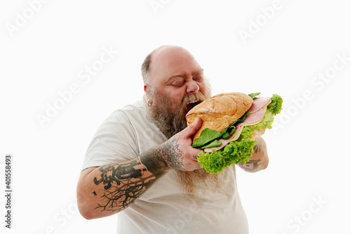 Hungry overweigh bearded man enjoying eating huge burger . Unhealthy food concept. photo