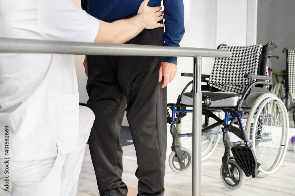 Naklejka premium Senior Man Being Assisted By Physiotherapist In Rehab Center. High quality photo