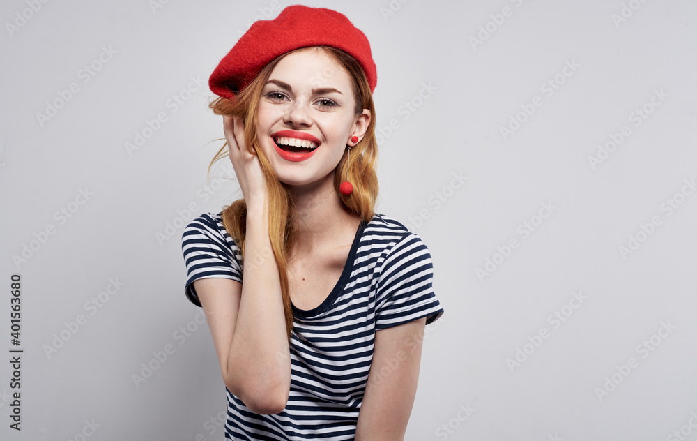 model in red hat and in a striped t-shirt on a light background emotions portrait cropped view