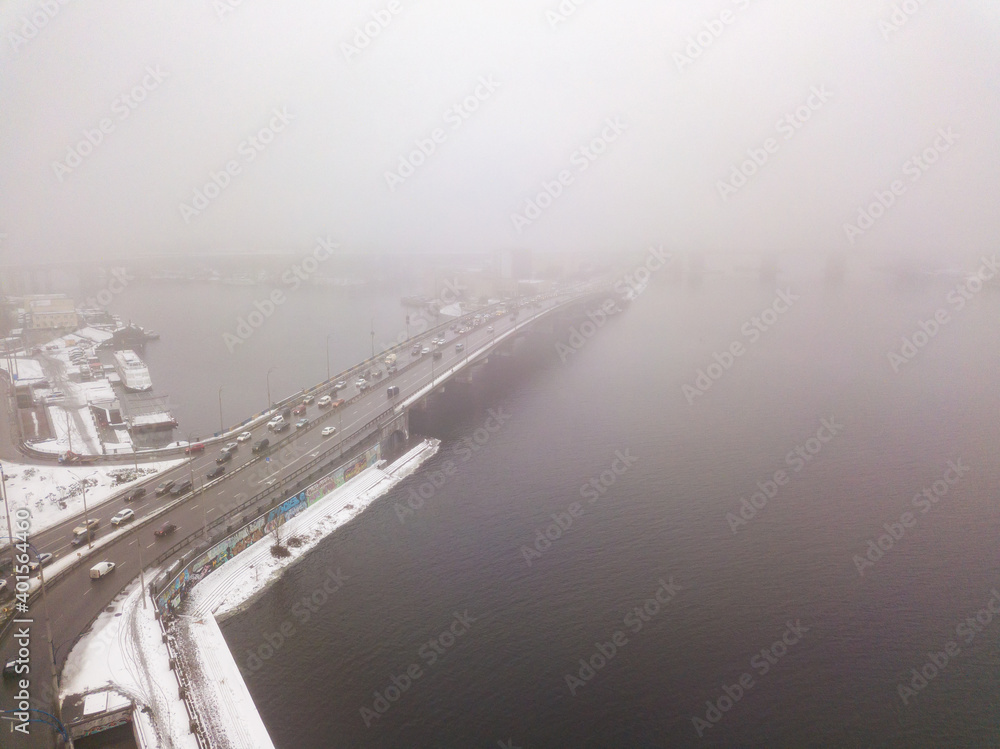 Aerial drone view. Automobile bridge over the Dnieper river in Kiev in the morning fog.