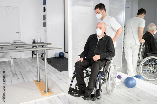 Male Nurse assisting a senior handicapped patient in wheelchair at rehabilitation center. High quality photo