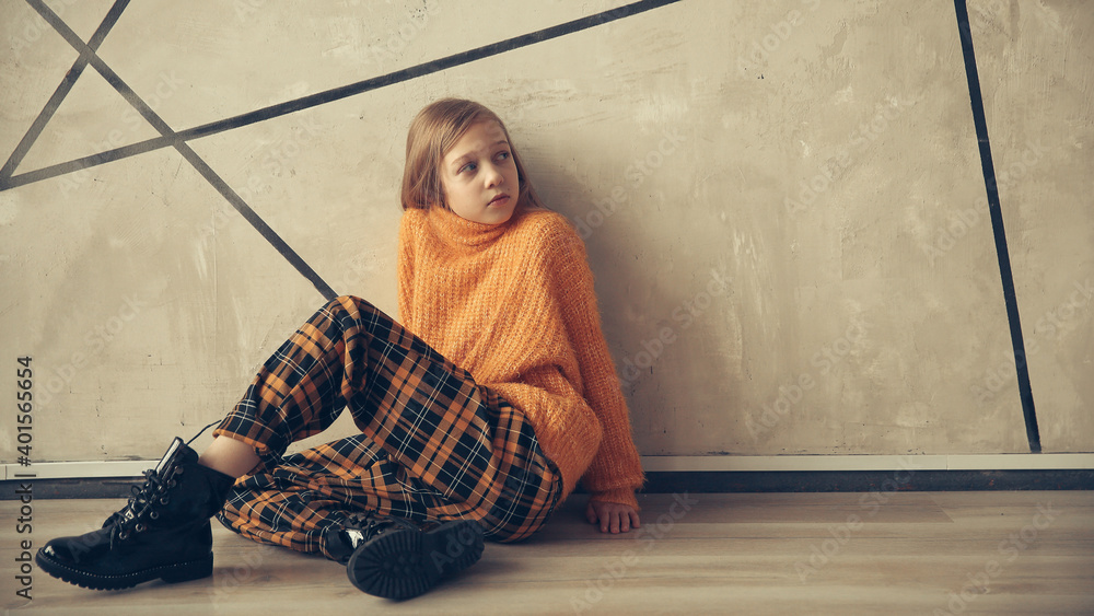 cute teen girl sitting near the wall.
