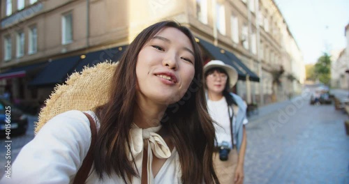 POV of beautiful young Asian female making video vlog outdoors on street. Woman traveler with mother in city video chatting in good mood. Urban tourism. Close up portrait. Blogger concept photo
