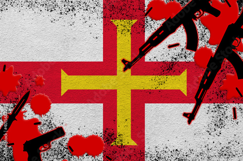 Guernsey flag and guns in red blood. Concept for terror attack and military operations photo