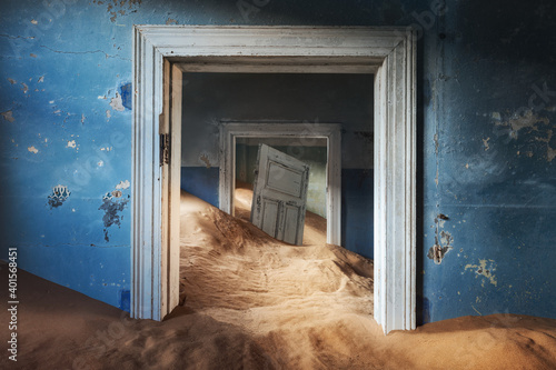 Abandoned building and the door being taken over by encroaching sand, Kolmanskop ghost town, Namib Desert