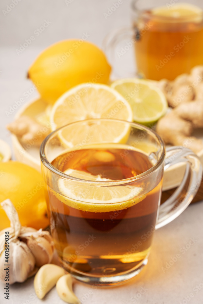 Hot herbal tea with ginger, garlic, lemon and honey vitamins C over grey background. Concept alternative medicine, natural homemade remedy for cold and flu. Support the immune system. Well-Being and Hot herbal tea with ginger, garlic, lemon and honey vitamins C over grey background. Concept alternative medicine, natural homemade remedy for cold and flu. Support the immune system. Well-Being and