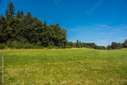 Green field with agriculture meadow and blue sky. Panoramic view to grass on the hill on sunny spring day