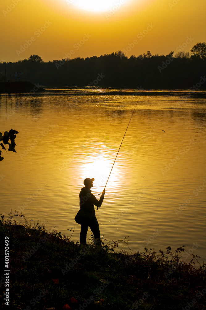 Angler in romantische Stimmung am Ufer eines Flusses im Sonnenuntergang