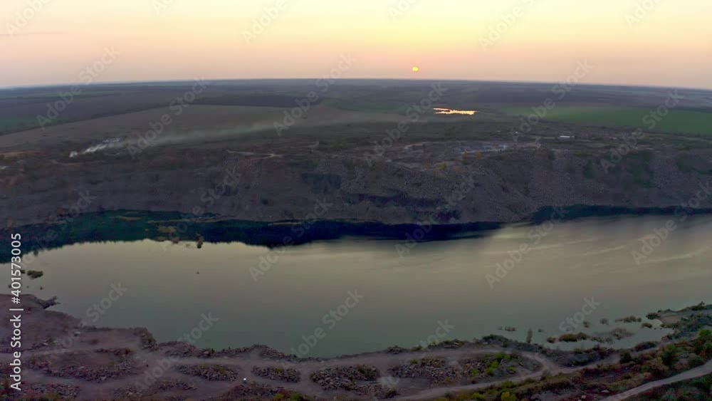 Old flooded stone quarry with large stones in the evening warm bright light covered with small dry plants in picturesque Ukraine. Aerial UHD 4K drone realtime video, shot in 10bit HLG and colorized Old flooded stone quarry with large stones in the evening warm bright light covered with small dry plants in picturesque Ukraine. Aerial UHD 4K drone realtime video, shot in 10bit HLG and colorized
