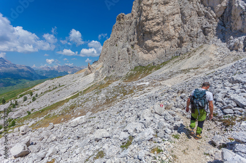 Unrecognizable man walking on a hiking trail with amazing dolomite peaks background, Settsass, Dolomites, Italy