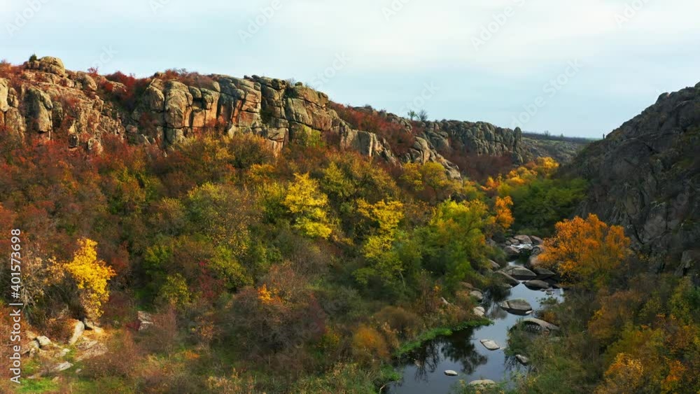 A stream flows in the Aktovsky Canyon, Ukraine. Autumn trees and large stone boulders around. Aerial UHD 4K drone realtime video, shot in 10bit HLG and colorized A stream flows in the Aktovsky Canyon, Ukraine. Autumn trees and large stone boulders around. Aerial UHD 4K drone realtime video, shot in 10bit HLG and colorized