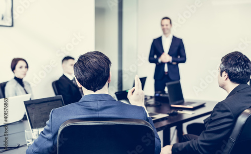 Successful team leader and business owner leading informal in-house business meeting. Businessman working on laptop in foreground. Business and entrepreneurship concept.