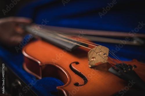 Musician delicately takes out his instrument from its blue case, the wood-colored violin in his hand is accommodated.