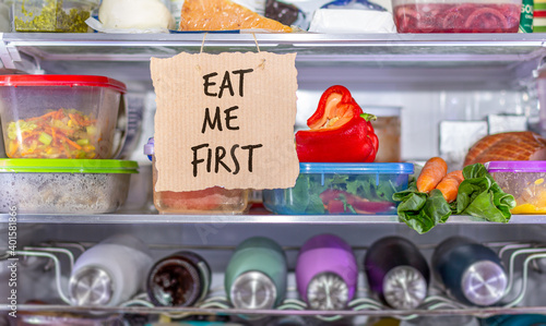 Eat Me First handmade sign in fridge, eat food first area to help reduce food waste, know where to look first, simple reduce food waste concept. photo