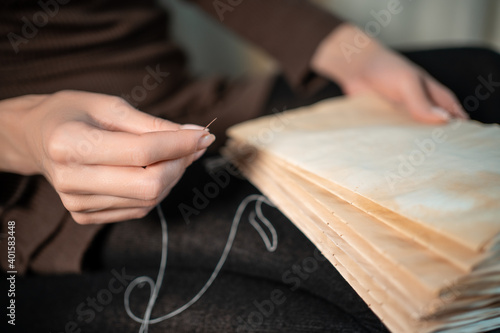 close up of female hands binding book at home or DIY make book with old paper