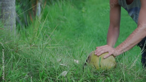  young man opens with knife ripe fresh coconut in Asia