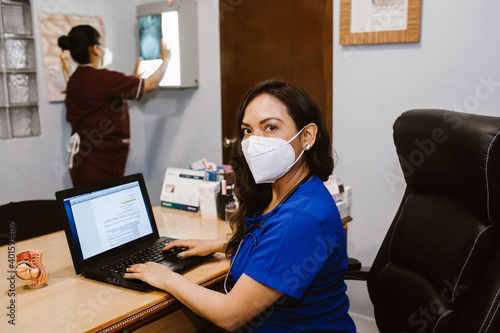 Latin female doctor working while sitting at desk in front of laptop in a Mexican hospital