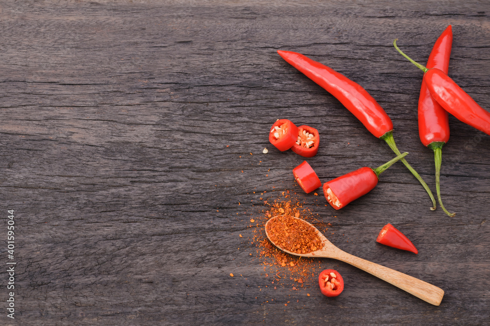 Cayenne pepper in a spoon And a bunch of bright red chili peppers on an old vintage wooden table Cayenne pepper in a spoon And a bunch of bright red chili peppers on an old vintage wooden table