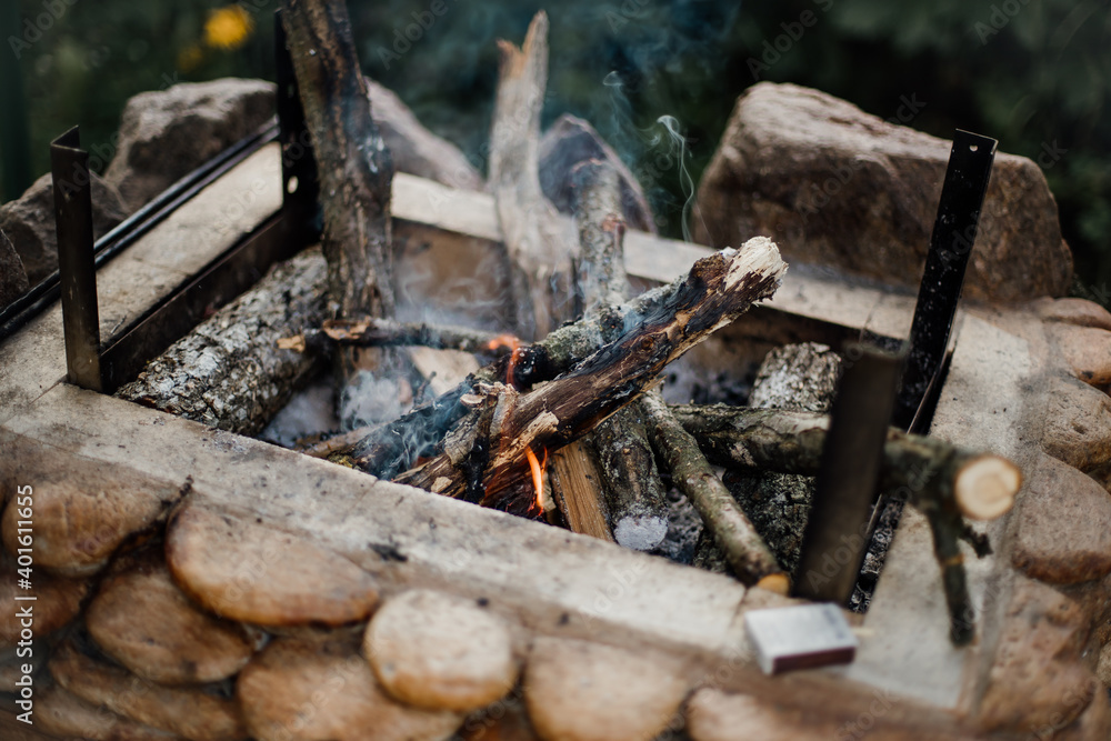 Fototapeta premium Bonfire lighted from wood in the grill at their summer cottage. Bright flame from the fire.