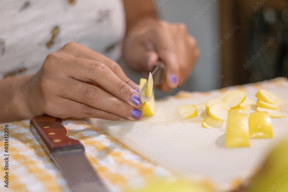 Cutting apple slices. Ingredients for making apple strudel. Latina cuts a yellow apple in half. 