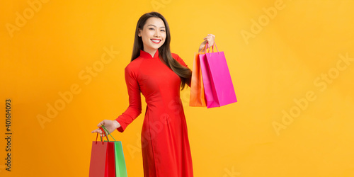 happy woman holding shopping bag on lunar new year celebration isolated on a yellow background