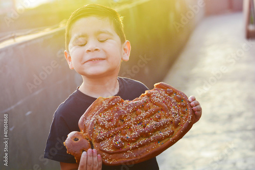 Bild auf Leinwand Latin kid with typical big sweet bread named tantawawa for All Saints Day