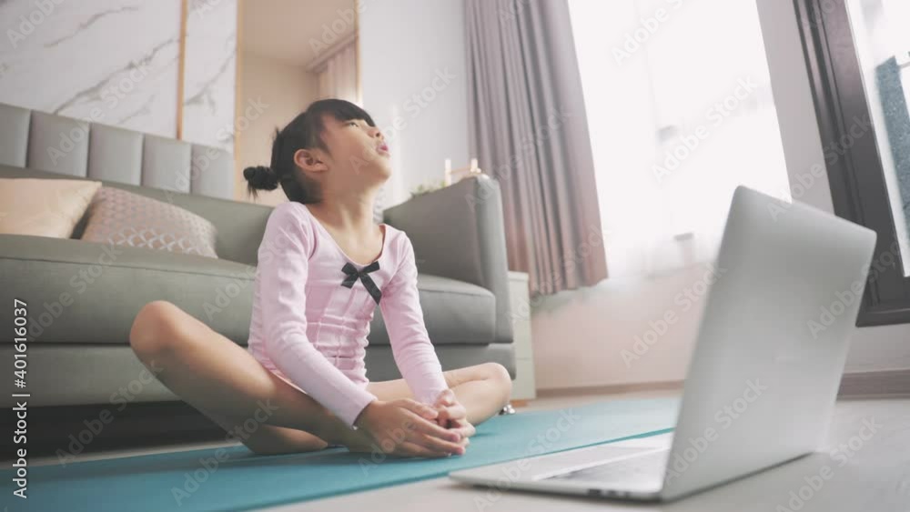Little asian girl doing yoga plank and watching online lessons on laptop, exercising in the kitchen. A child plays sports during the COVID-19 pandemic.
Little asian girl doing yoga plank and watching online lessons on laptop, exercising in the kitchen. A child plays sports during the COVID-19 pandemic.
