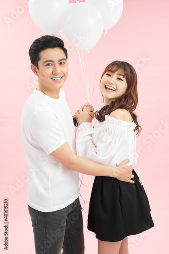 Happy young couple with balloons isolated on pink. Valentine's day celebration