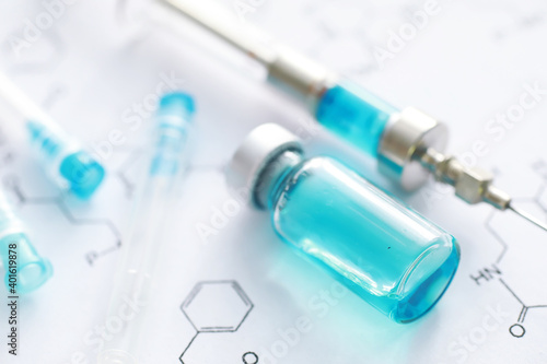 small jars with injection and syringe for injection on a blue background near the chemical formula