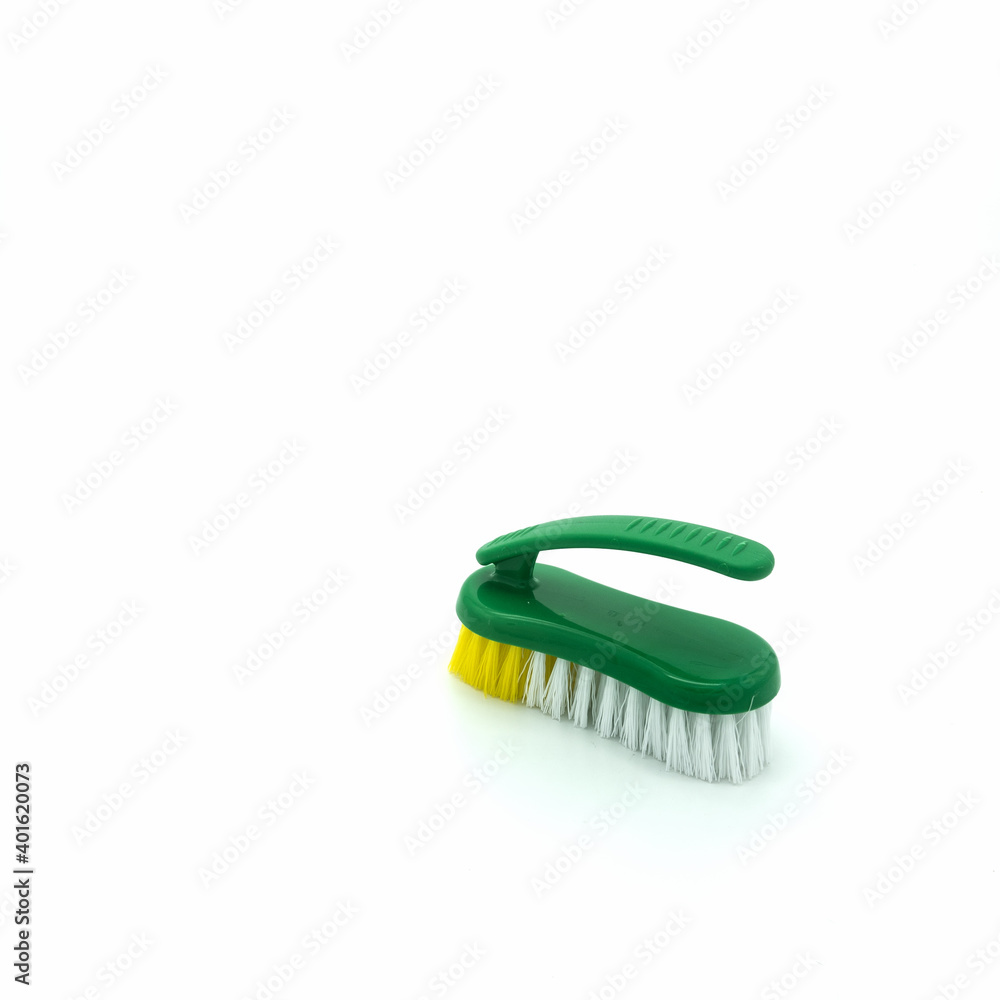 Plastic brush for cleaning the house. Green base, ribbed, non-slip handle. The bristles are thick and long, white and yellow. Isolated on white background. Bottom right corner. Plastic brush for cleaning the house. Green base, ribbed, non-slip handle. The bristles are thick and long, white and yellow. Isolated on white background. Bottom right corner.
