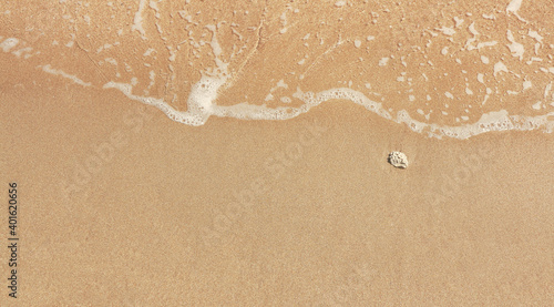 Beach with champagne color and a big stone on the right side. Close up top view.