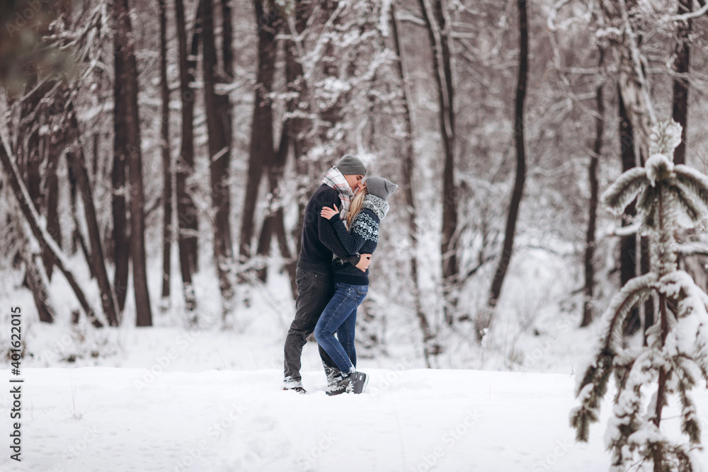 The guy hugs the girl and kisses in the snowy winter forest
