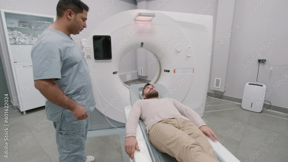 Handheld tracking of medical tech in scrubs performing CT scan procedure of patient in radiology room in hospital Handheld tracking of medical tech in scrubs performing CT scan procedure of patient in radiology room in hospital