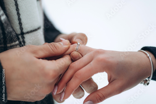 The guy puts the engagement ring on the hand of his girlfriend by making an offer to get married