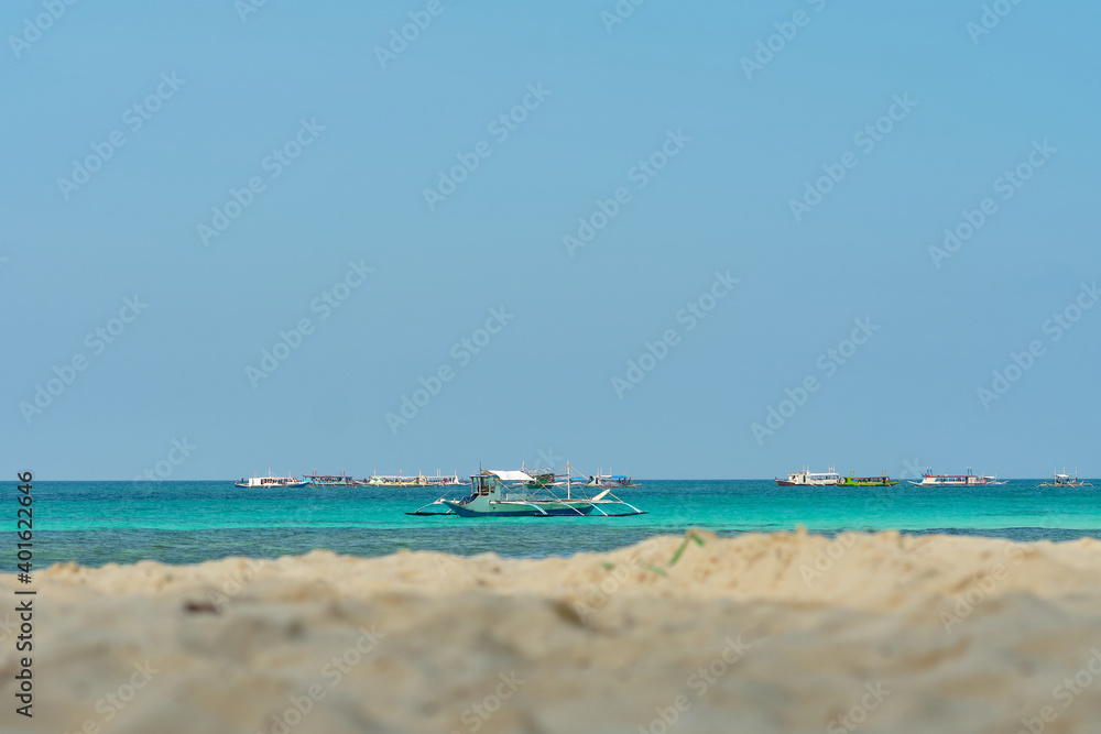 Empty White beach of Boracay island in the daytime. No Chinese tourists because of the coronavirus. Boats in the sea carry tourists.