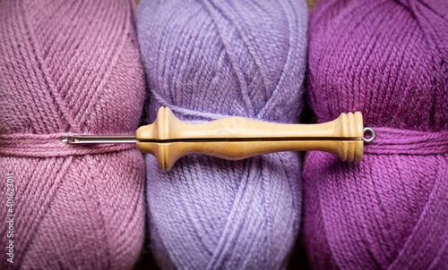 A wood punch needle tool on 3 wool balls in purple tones 