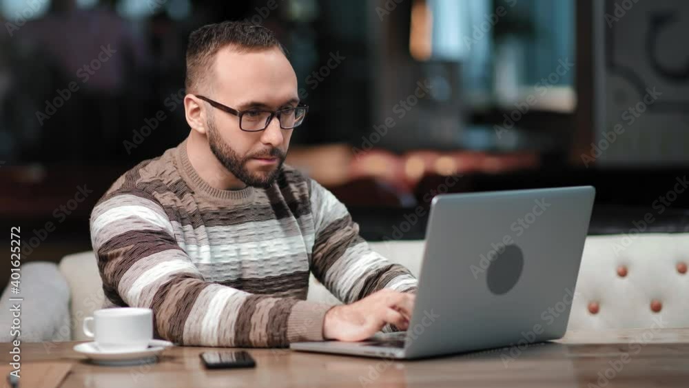 Busy business guy working surfing internet on laptop pc at cafe. Shot on RED Raven 4k Cinema Camera Busy business guy working surfing internet on laptop pc at cafe. Shot on RED Raven 4k Cinema Camera