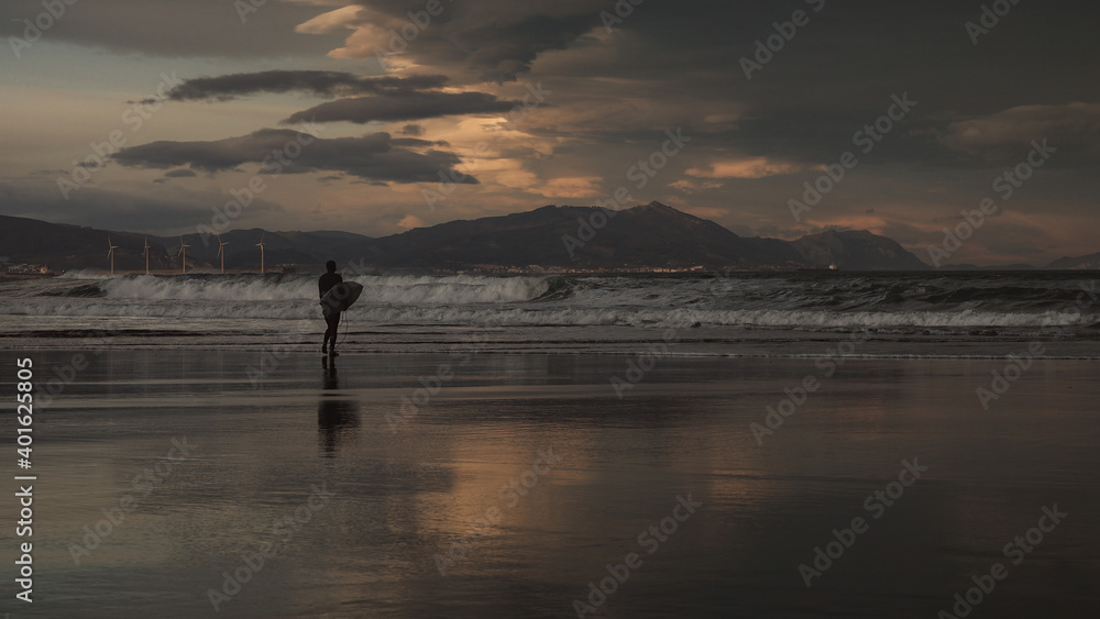 Surfer on the beach enjoying a beautiful sunset