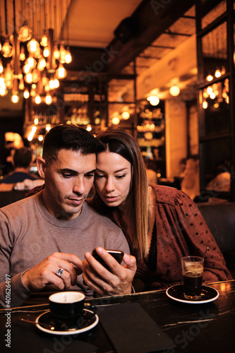 Young couple using mobile phone at restaurant.