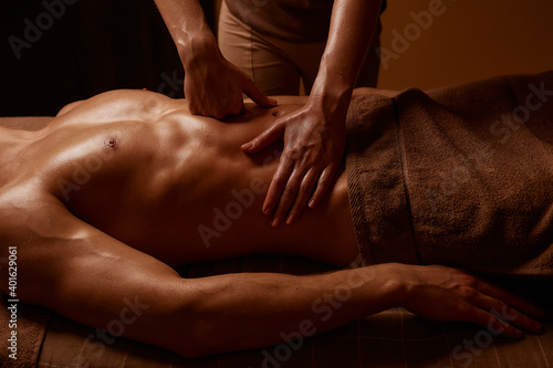 Girl doing massage to a muscular man in a spa salon