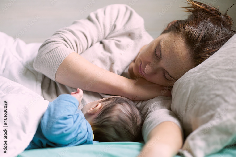 middle-aged woman lying with her two-month-old baby in bed resting. motherhood concept