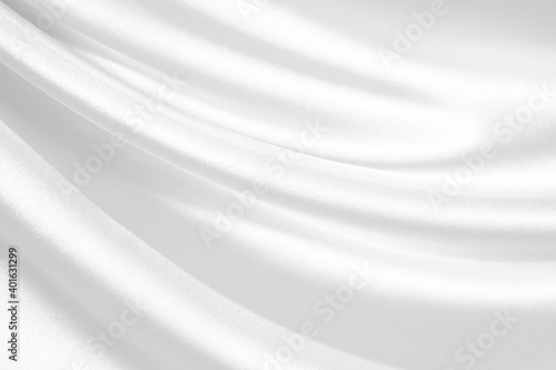 White abstract background. White satin silk texture background. Beautiful soft wavy folds on the fabric. White elegant background.