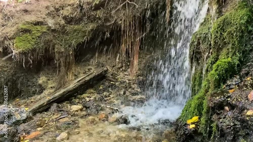Slow-motion footage of a forest waterfall with clean, clear drinking water on a sunny summer day