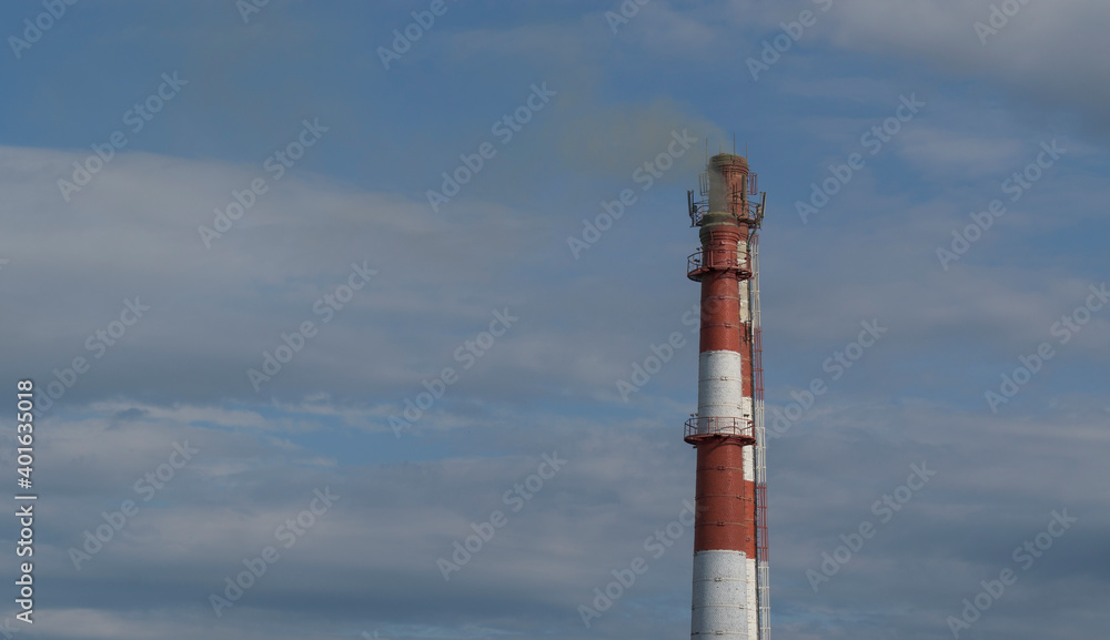 Two pipes on the background of the sky with clouds. Gray smoke. The pipe material is white and red bricks. Two pipes on the background of the sky with clouds. Gray smoke. The pipe material is white and red bricks.