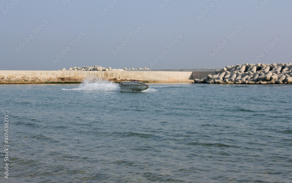 Sea landscape with boat and breakwater.