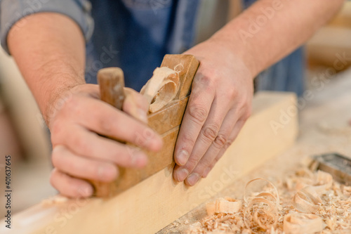 Close up carpenter's hands planed wood in a workshop