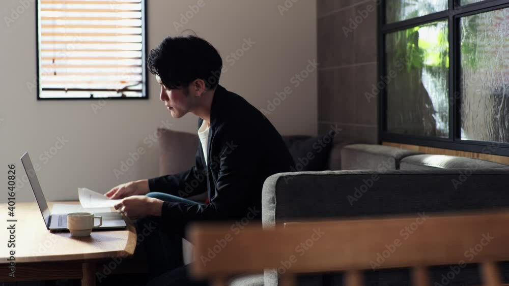 リビングのソファでリモートワークをする日本人の男性 リビングのソファでリモートワークをする日本人の男性
