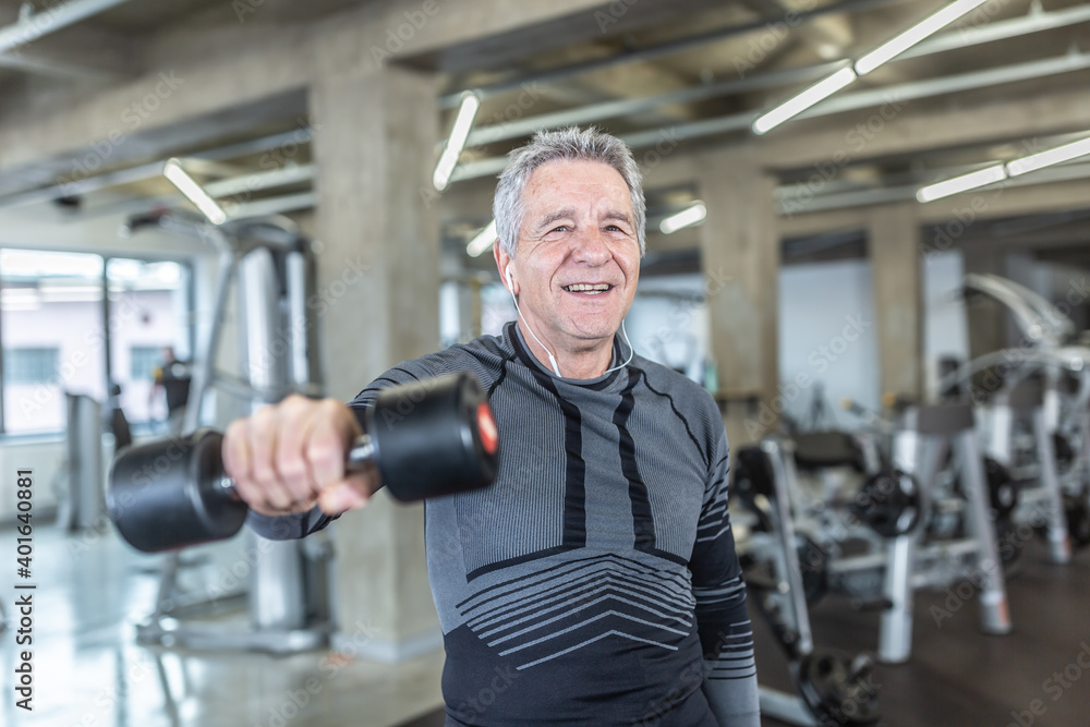 Losing weight and gainiong strength by a dumbell training performed by older man in the fitness center Losing weight and gainiong strength by a dumbell training performed by older man in the fitness center